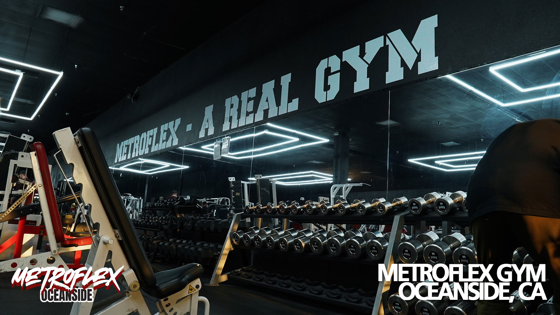 A long rack of dumbbells in front of the mirrored wall at MetroFlex Oceanside.